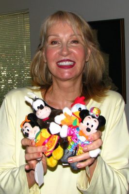 Alyja holds dolls wearing her costumes she designed for a parade. These were sold in Tokyo Disneyland.